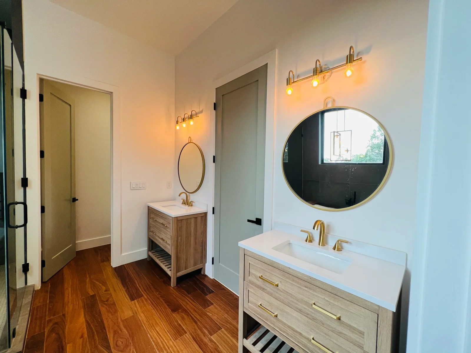 Dual vanity bathroom with quartz countertops, wood cabinetry, brass mirrors and lighting fixtures