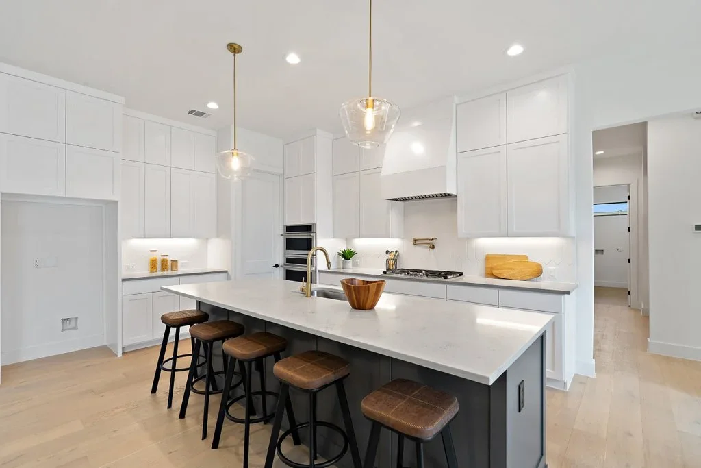 Modern kitchen with white cabinetry, dark island, white quartz counters, and stainless steel appliances
