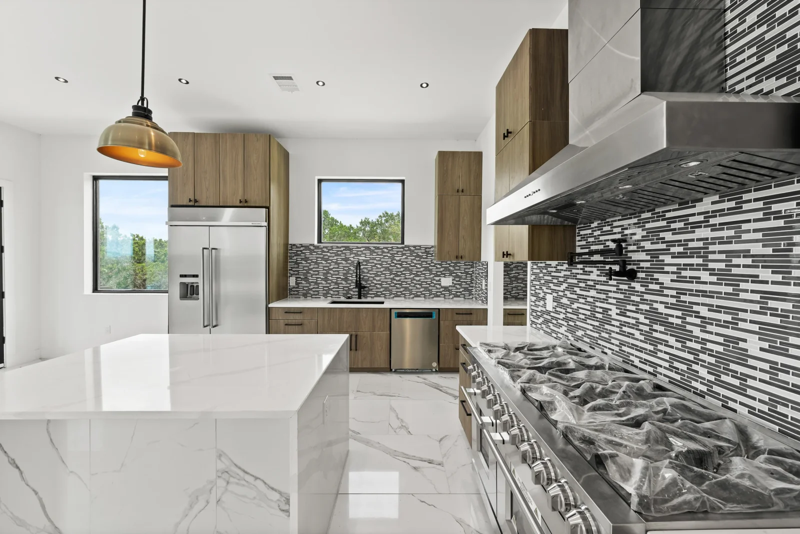 Modern kitchen with walnut cabinets, white quartz counters, black and white tile backsplash, stainless steel appliances