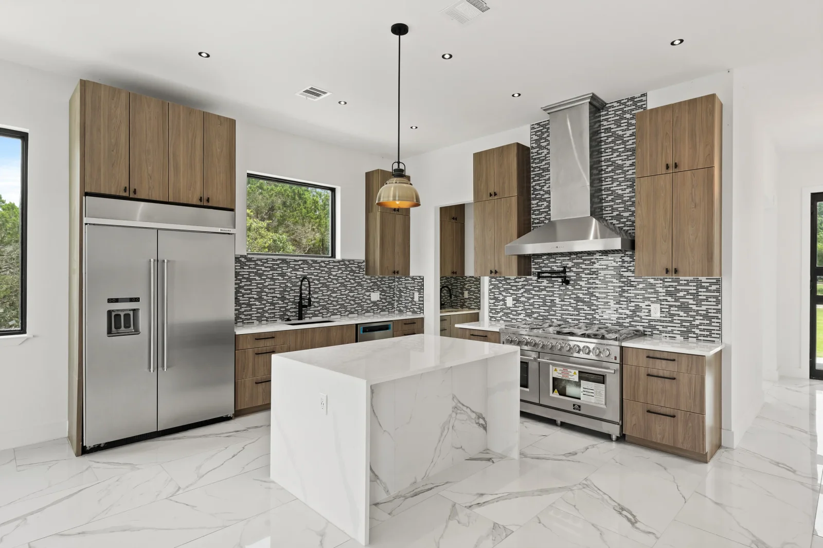 Modern kitchen with wood cabinets, marble countertops, glass tile backsplash, and stainless steel appliances