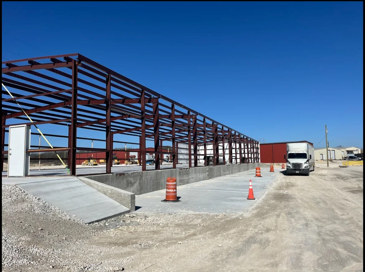 Steel frame commercial building with concrete foundation, metal roof decking, and structural columns under construction